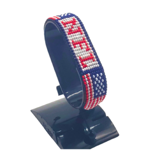 Handcrafted USA flag bracelet made with red and white beads, adjustable beaded wrist accessory, displayed on a black stand.