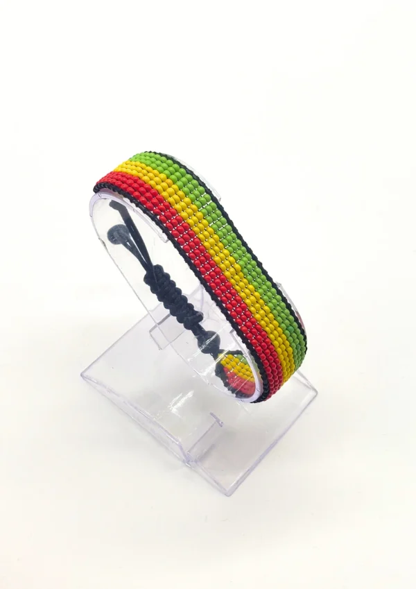 Handcrafted Guinea flag bracelet made with red and white beads, adjustable beaded wrist accessory, displayed on a Clear stand
