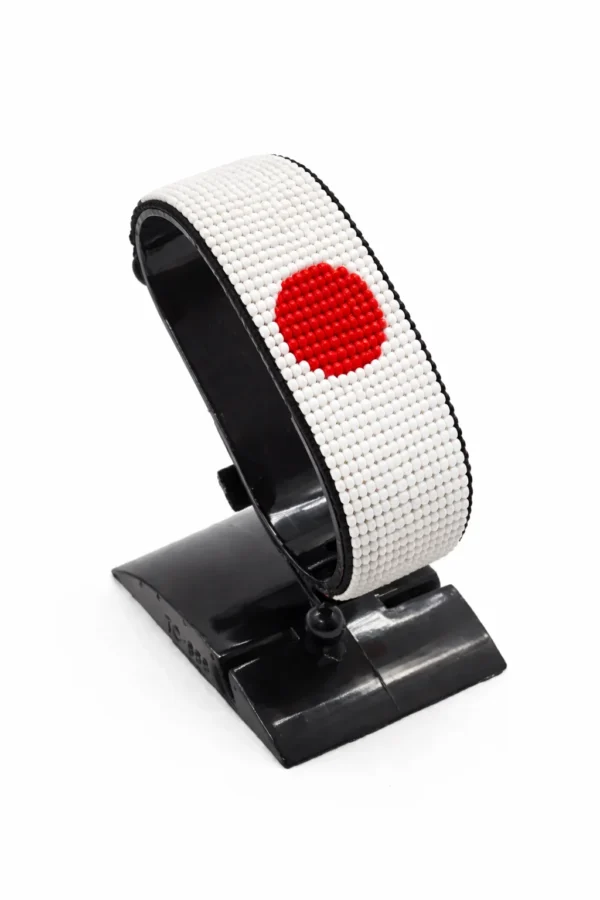 Handcrafted Japan flag bracelet with red and white beads, adjustable beaded wrist accessory, displayed on a black stand.