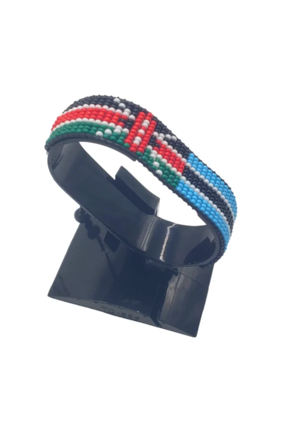 Handcrafted Kenya flag bracelet made with red and white beads, adjustable beaded wrist accessory, displayed on a black stand