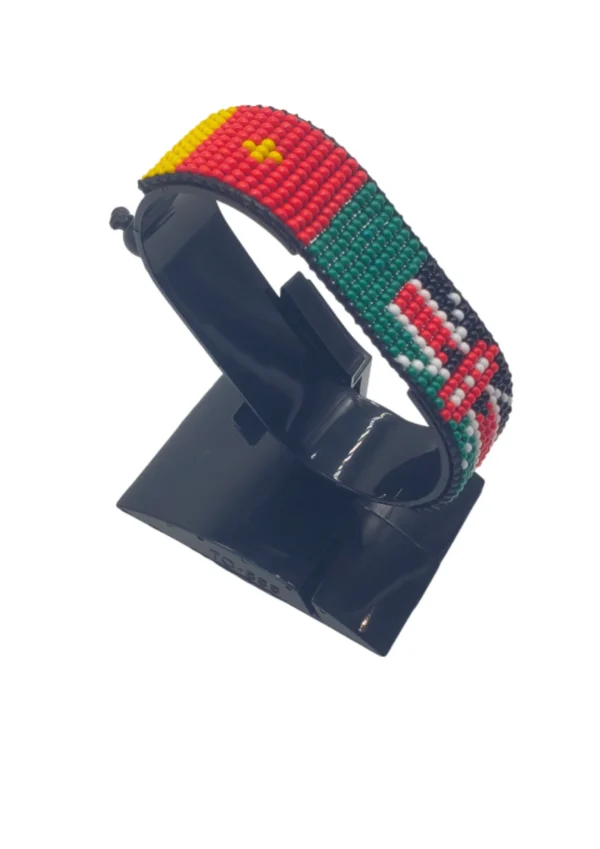 Handcrafted Kenya flag bracelet made with red and white beads, adjustable beaded wrist accessory, displayed on a black stand