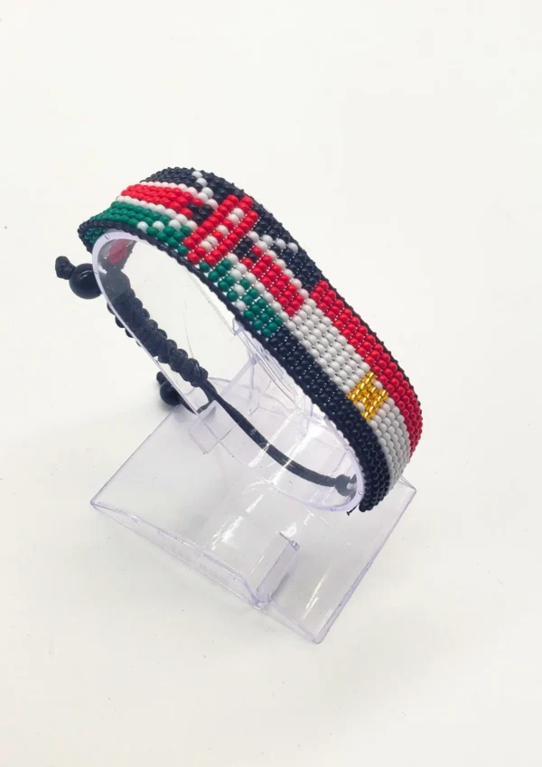 Handcrafted Kenya Egypt flag bracelet made with red and white beads, adjustable beaded wrist accessory, displayed on a Clear stand
