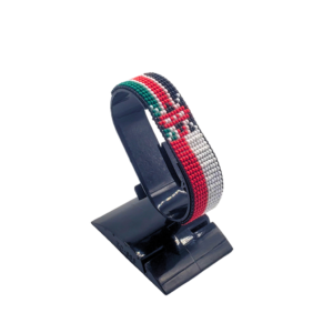 Handcrafted Kenya Austria flag bracelet made with red and white beads, adjustable beaded wrist accessory, displayed on a black stand
