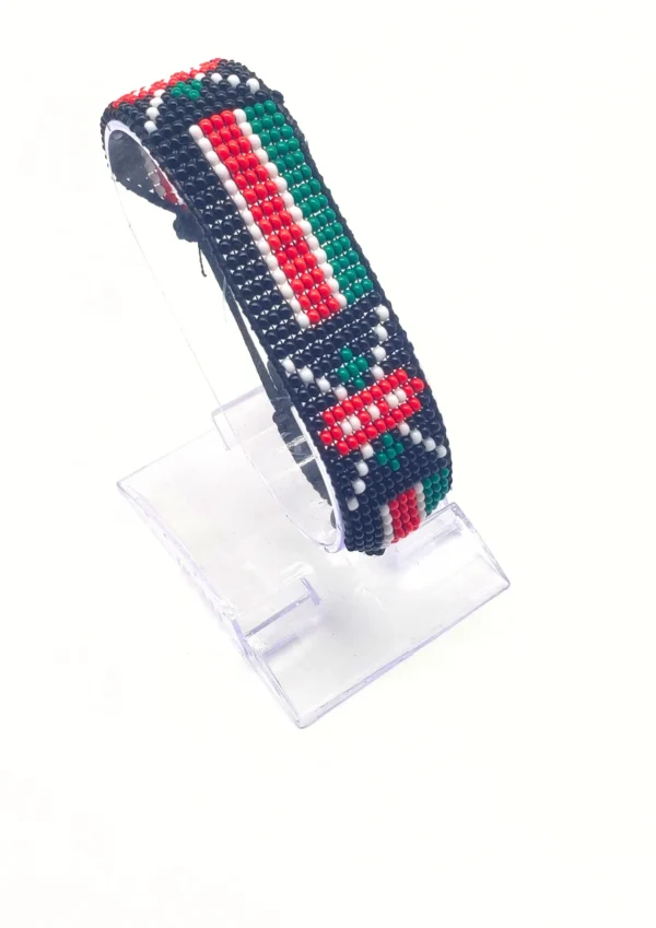 Handcrafted Kenya flag bracelet made with red and white beads, adjustable beaded wrist accessory, displayed on a black stand