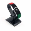 Handcrafted Libya flag bracelet made with red and white beads, adjustable beaded wrist accessory, displayed on a black stand
