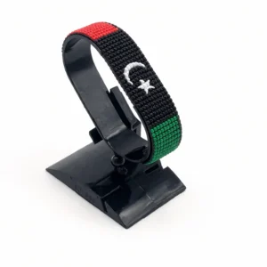 Handcrafted Libya flag bracelet made with red and white beads, adjustable beaded wrist accessory, displayed on a black stand