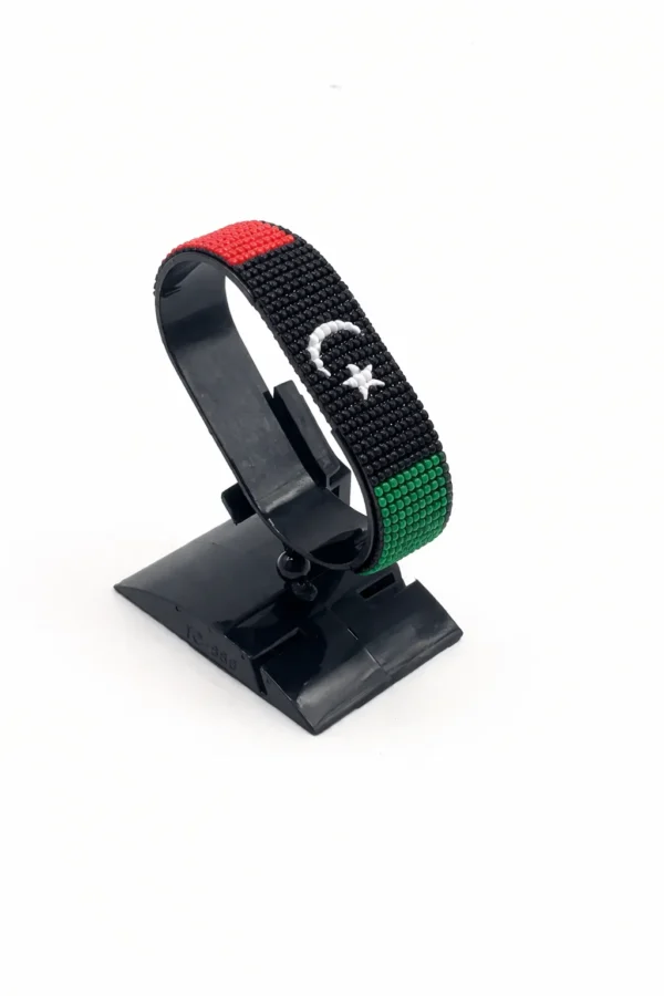 Handcrafted Libya flag bracelet made with red and white beads, adjustable beaded wrist accessory, displayed on a black stand