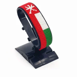 Handcrafted Oman flag bracelet made with red and white beads, adjustable beaded wrist accessory, displayed on a black stand