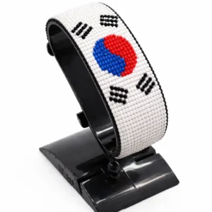 Handcrafted South Korea flag bracelet made with red and white beads, adjustable beaded wrist accessory, displayed on a black stand