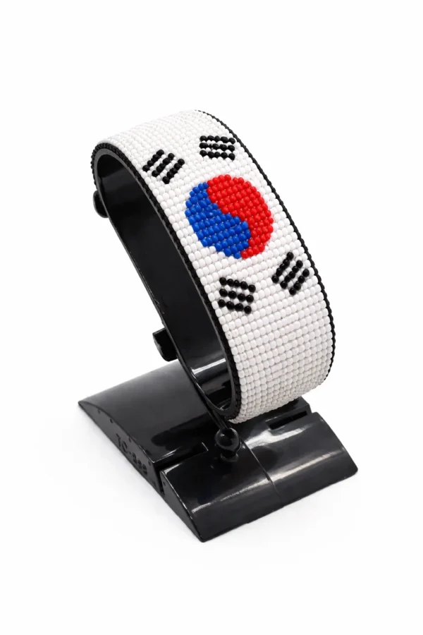 Handcrafted South Korea flag bracelet made with red and white beads, adjustable beaded wrist accessory, displayed on a black stand