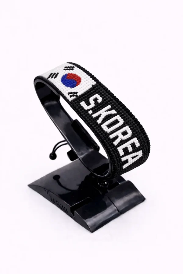 Handcrafted South Korea flag bracelet made with red and white beads, adjustable beaded wrist accessory, displayed on a black stand