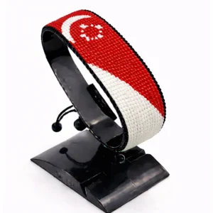 Handcrafted Singapore flag bracelet made with red and white beads, adjustable beaded wrist accessory, displayed on a black stand