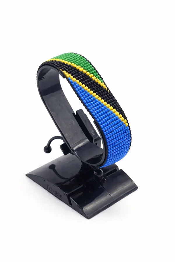 Handcrafted Tanzania flag bracelet, adjustable beaded wrist accessory, displayed on a black stand.