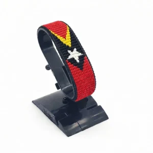 Handcrafted The Timor-Leste flag bracelet, adjustable beaded wrist accessory, displayed on a black stand.