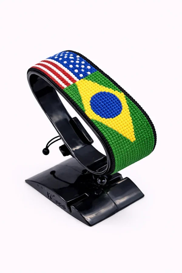 Handcrafted USA BRAZIL Combo flag bracelet made with red and white beads, adjustable beaded wrist accessory, displayed on a Black stand.