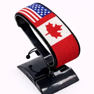 Handcrafted USA CANADA Combo flag bracelet made with red and white beads, adjustable beaded wrist accessory, displayed on a Black stand.