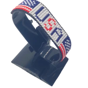 Handcrafted USA flag bracelet made with red and white beads, adjustable beaded wrist accessory, displayed on a black stand.