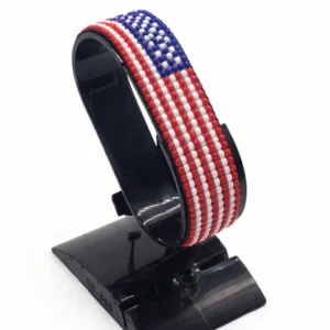 Handcrafted USA flag bracelet made with red and white beads, adjustable beaded wrist accessory, displayed on a black stand.