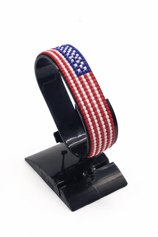 Handcrafted USA flag bracelet made with red and white beads, adjustable beaded wrist accessory, displayed on a black stand.