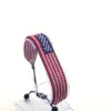 Handcrafted USA flag bracelet made with red and white beads, adjustable beaded wrist accessory, displayed on a black stand.