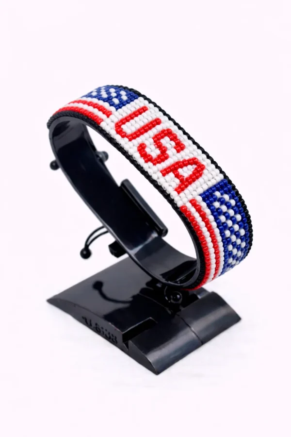 Handcrafted USA flag bracelet made with red and white beads, adjustable beaded wrist accessory, displayed on a black stand.