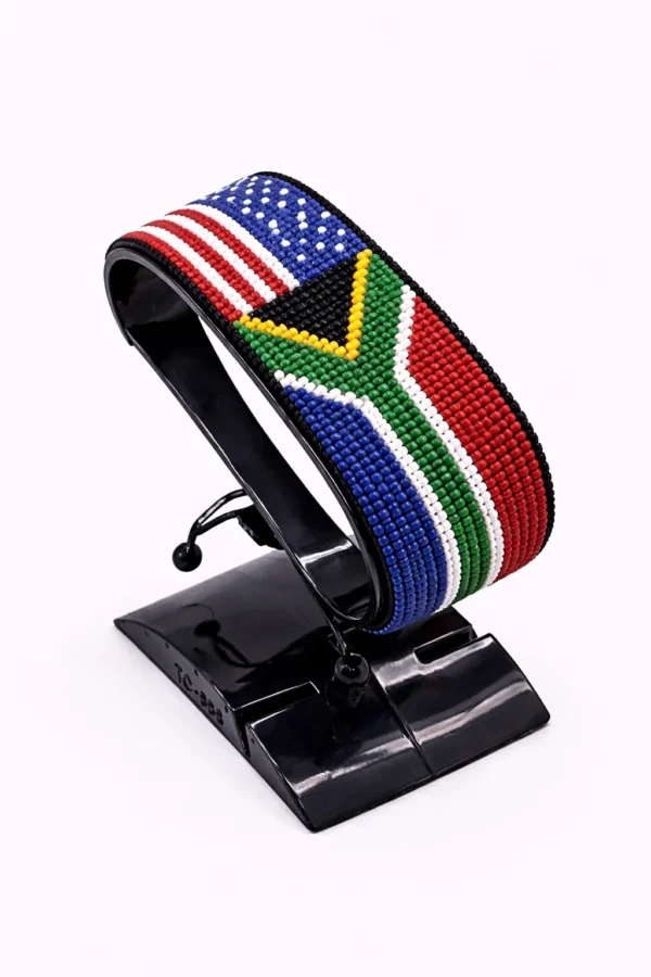 Handcrafted USA South Africa Combo flag bracelet made with red and white beads, adjustable beaded wrist accessory, displayed on a Clear stand.