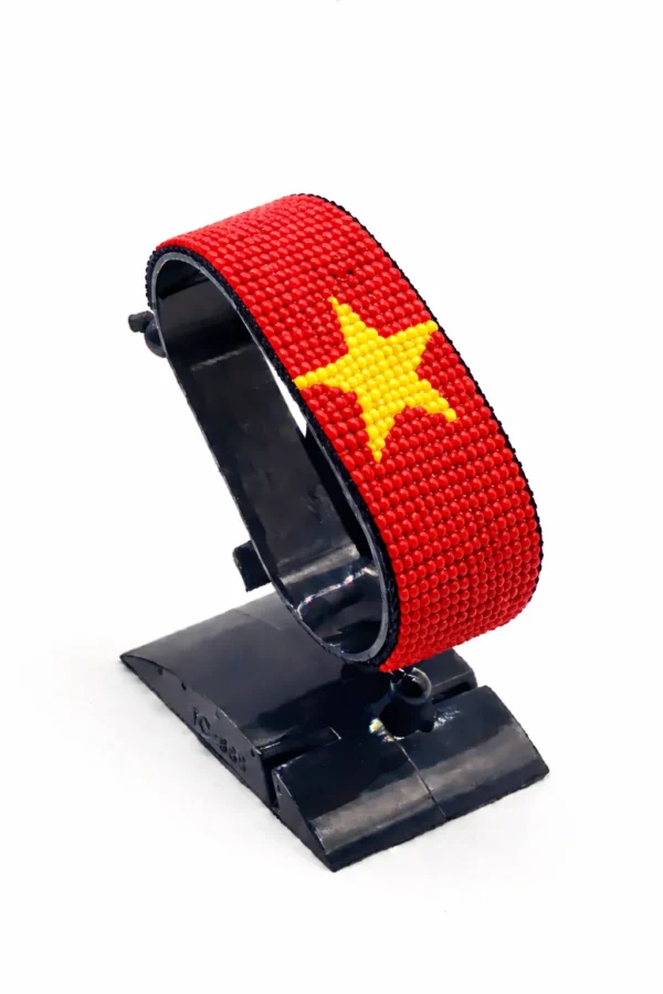 Handcrafted Vietnam flag bracelet made with red and yellow beads, adjustable beaded wrist accessory, displayed on a black stand.