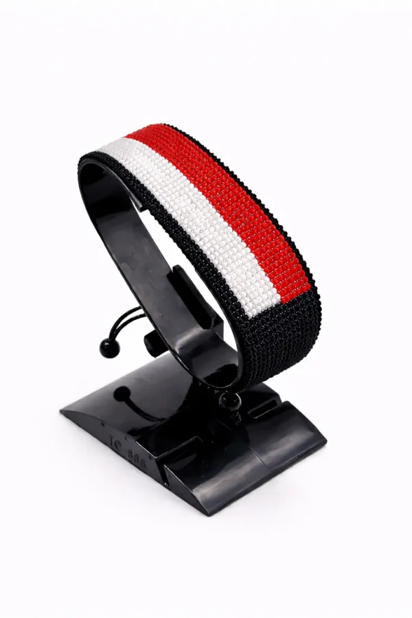 Handcrafted Yemen flag bracelet made with red, white, and black beads, adjustable beaded wrist accessory, displayed on a black stand.