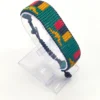 Handcrafted Zambia flag bracelet made with fine beads in green, red, black, and orange, adjustable beaded wrist accessory, displayed on a Clear stand.