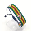 Handcrafted Zimbabwe flag bracelet made with green, yellow, red, black, and white beads, adjustable beaded wrist accessory, displayed on a Clear stand.