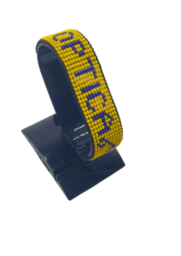 Optica Flag bracelet handcrafted in authentic Corporate colors on Black Stand.